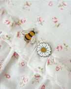 Weiße, kurzärmlige Bluse mit feinem Blumenmuster und grüner Schleife am Ausschnitt. mit binen und blumen pin